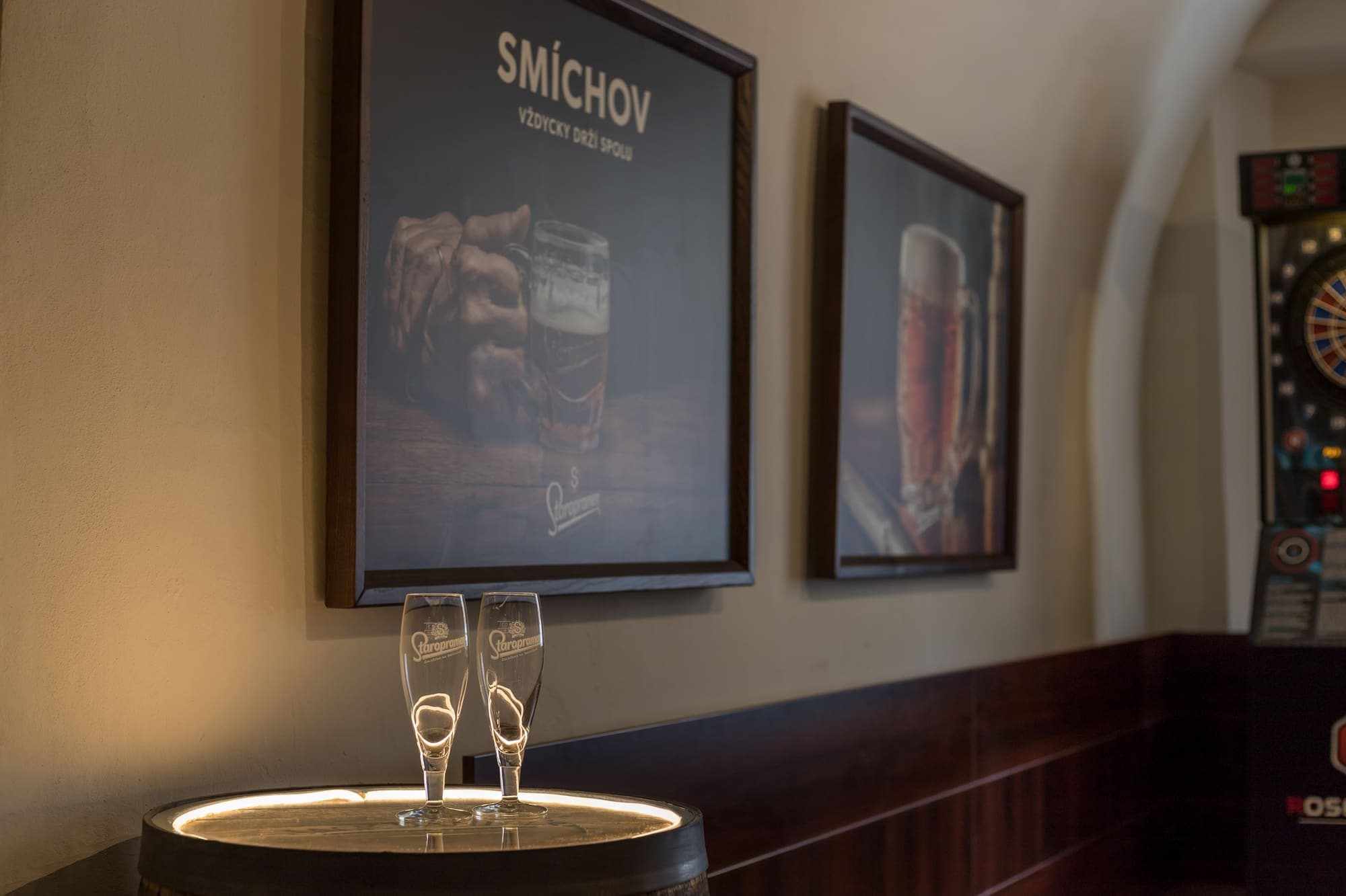 Plakáty Smíchov, sklenice Staropramen a šipkový automat